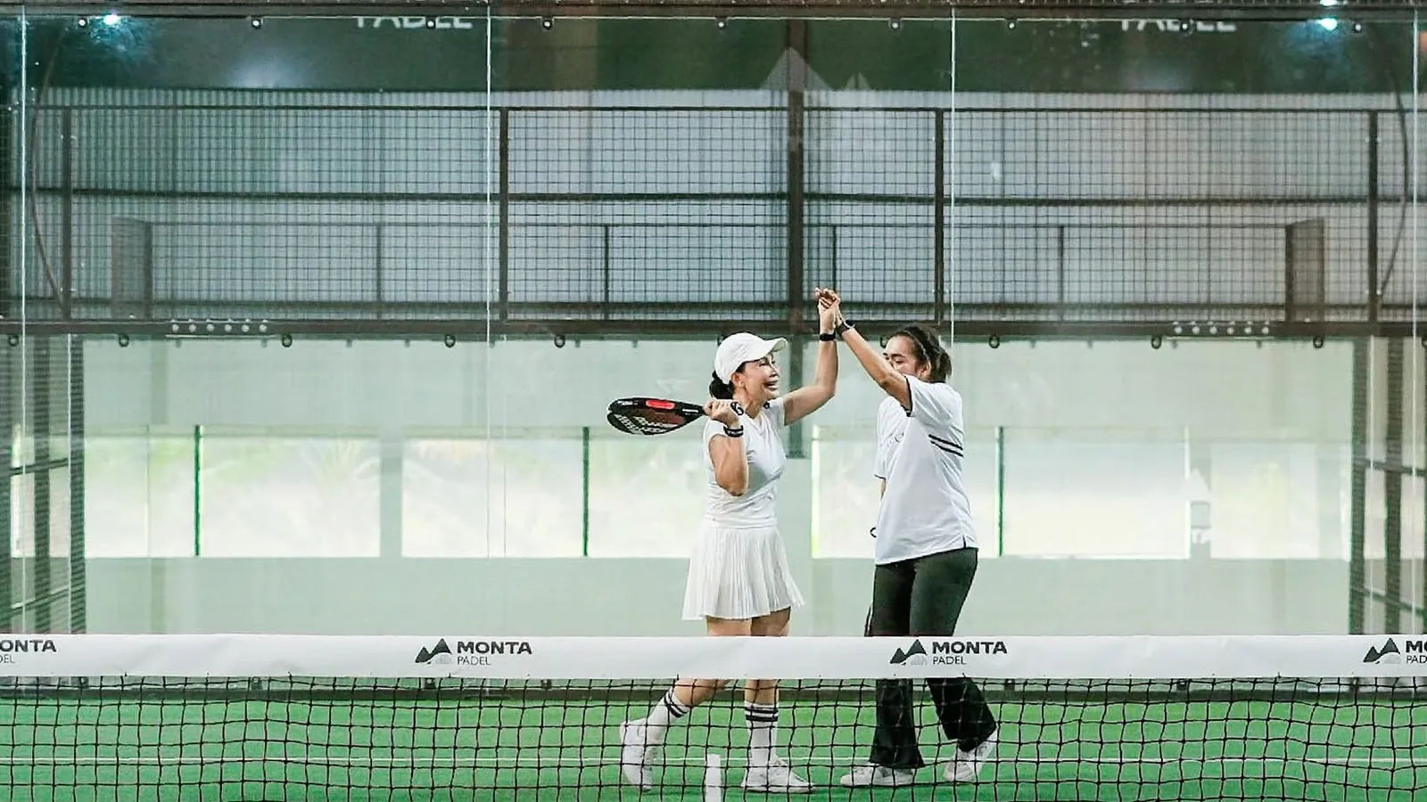 Two club players in white sharing a high-five across the net