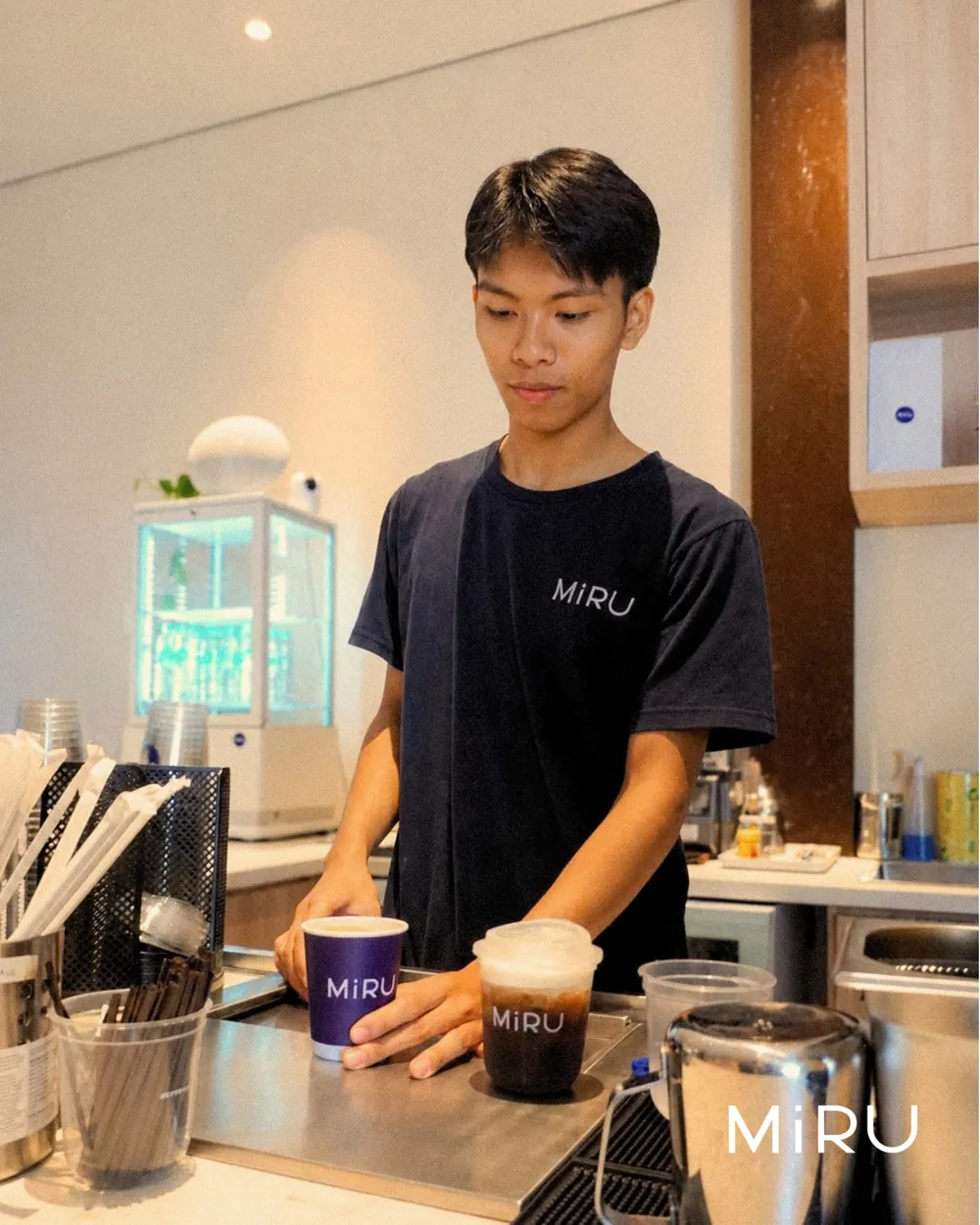 A Miru barista finishing two coffees at the bar