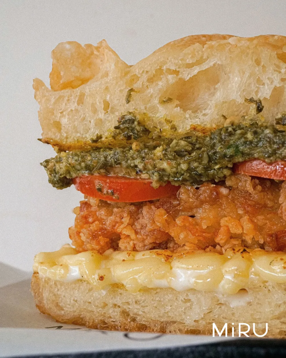 A crispy chicken focaccia with pesto, cut to show its layers