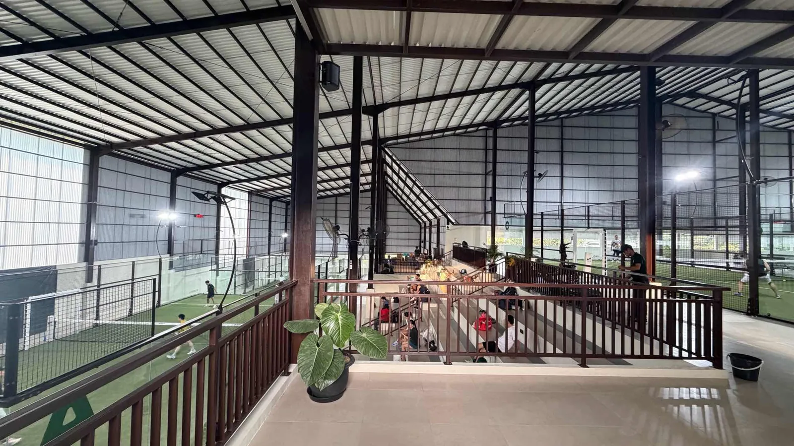 The upper deck's dark railing and plants, overlooking the lower courts